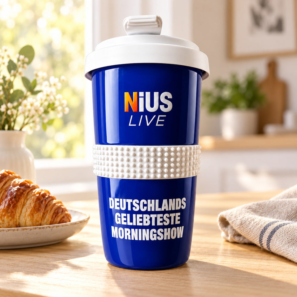 NIUS LIVE Coffee-to-Go-Becher auf einem Holztisch neben Croissant und Blumenvase am Frühstückstisch
